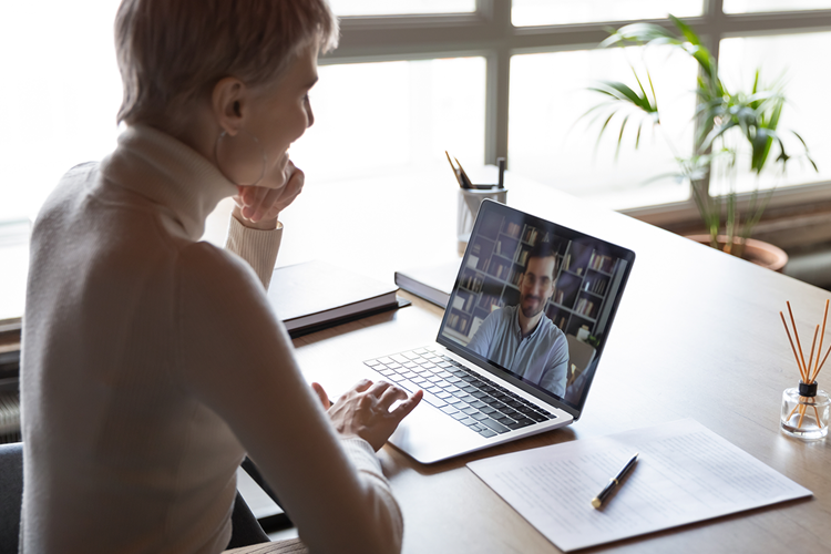 Kvinde afholder online-møde med kollega via computeren